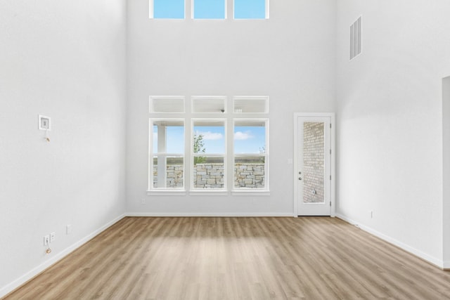 4419 College Square Dr, Round Rock, TX 78665 - unfurnished living room featuring baseboards, visible vents, wood finished floors, and a towering ceiling
