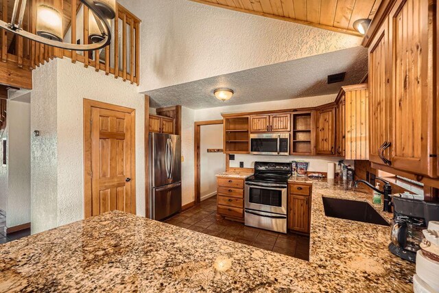 kitchen featuring open shelves, brown cabinets, appliances with stainless steel finishes, and a sink