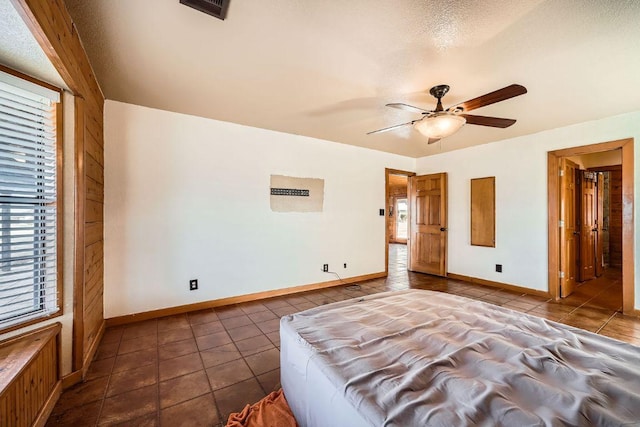 unfurnished bedroom with dark tile patterned floors, baseboards, visible vents, and a textured ceiling