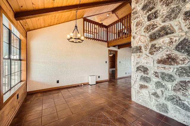 unfurnished room with lofted ceiling with beams, dark tile patterned floors, wood ceiling, and a chandelier