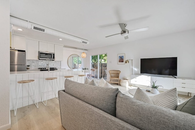 living area featuring light wood finished floors, visible vents, and a ceiling fan