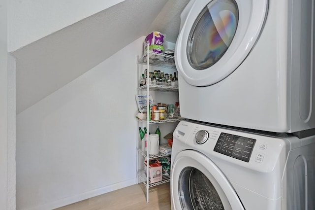 washroom with laundry area, wood finished floors, stacked washer / drying machine, and baseboards