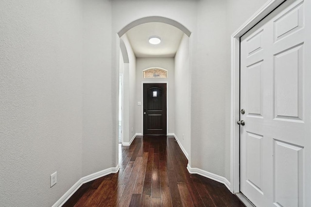 doorway featuring hardwood / wood-style flooring, baseboards, and arched walkways