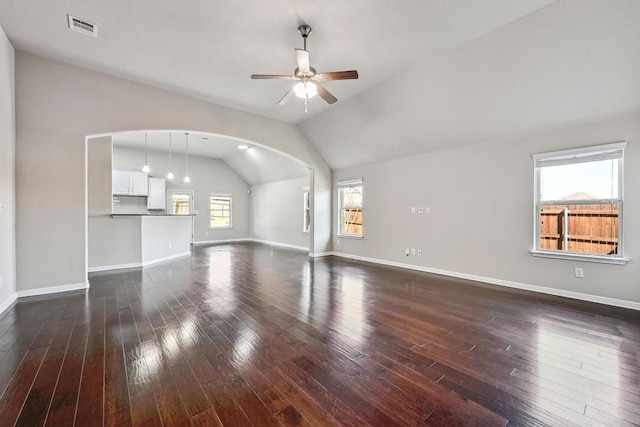 unfurnished living room with a ceiling fan, dark wood-style floors, visible vents, baseboards, and lofted ceiling