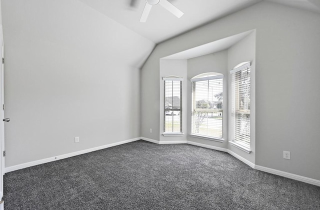 unfurnished room featuring dark colored carpet, baseboards, lofted ceiling, and a ceiling fan