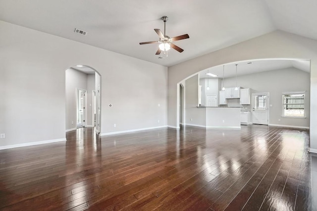 unfurnished living room featuring visible vents, arched walkways, dark wood-type flooring, and ceiling fan