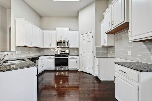 kitchen with tasteful backsplash, stainless steel appliances, dark stone counters, and a sink