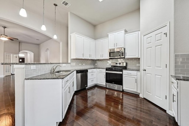 kitchen featuring visible vents, dark stone counters, a sink, white cabinets, and appliances with stainless steel finishes