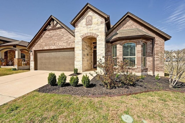 french country inspired facade featuring stone siding, an attached garage, brick siding, and driveway