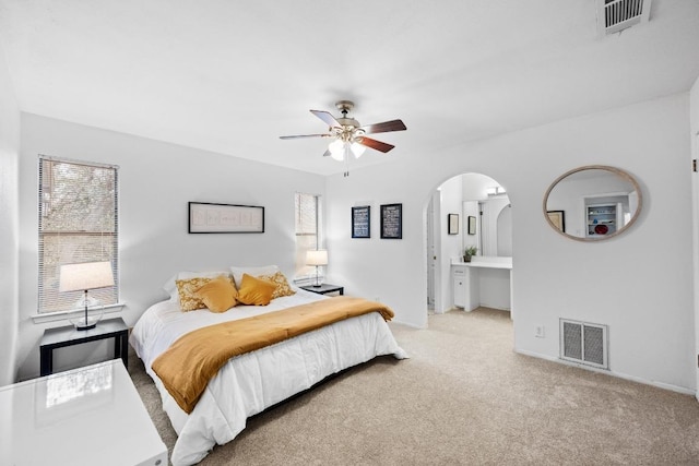 carpeted bedroom featuring visible vents, arched walkways, baseboards, and ceiling fan