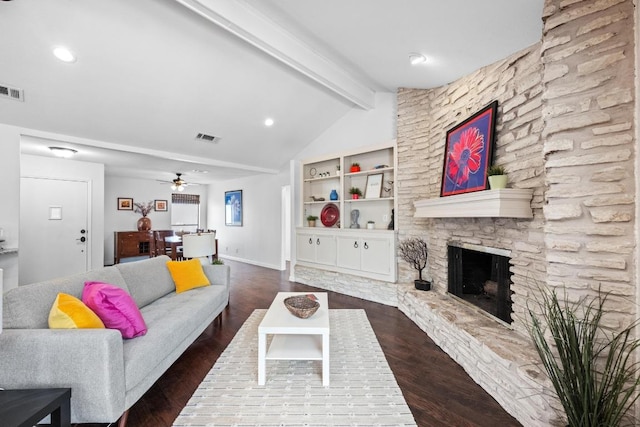 living area featuring wood finished floors, visible vents, a ceiling fan, vaulted ceiling with beams, and a stone fireplace