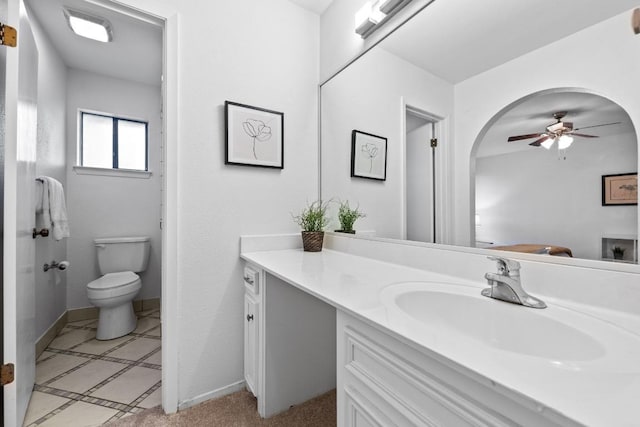 bathroom featuring toilet, vanity, baseboards, and ceiling fan