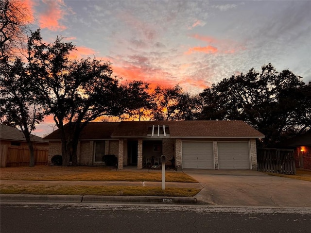 view of front of house featuring an attached garage, concrete driveway, a yard, and fence