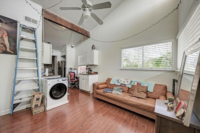 living area featuring visible vents, vaulted ceiling, dark wood-style floors, washer / clothes dryer, and a textured ceiling