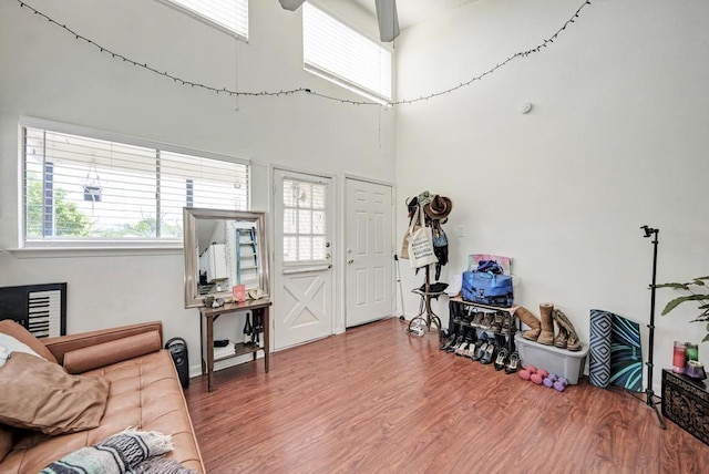 living area featuring wood finished floors, a towering ceiling, and ceiling fan