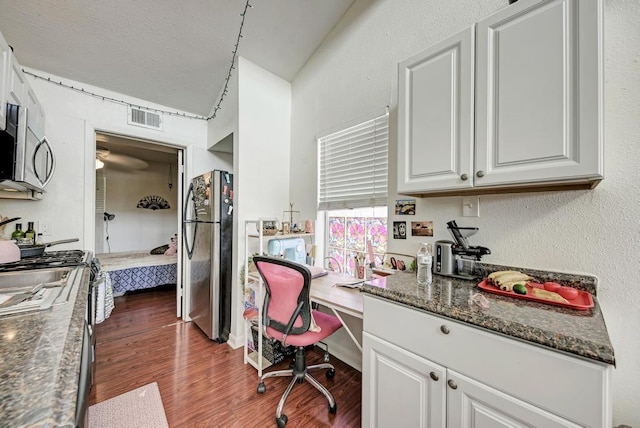 kitchen with visible vents, stainless steel microwave, wood finished floors, freestanding refrigerator, and white cabinets