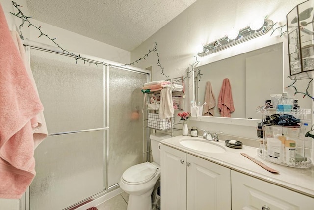 full bathroom featuring vanity, tile patterned flooring, a shower stall, a textured ceiling, and toilet