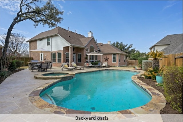 view of swimming pool featuring a pool with connected hot tub, a patio area, and a fenced backyard