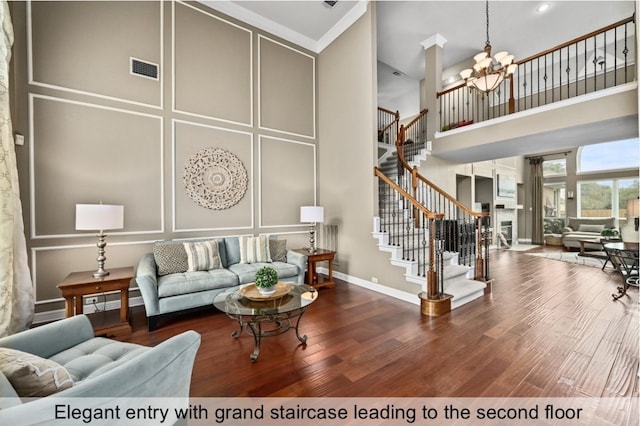 living room featuring a towering ceiling, wood finished floors, stairs, and a decorative wall