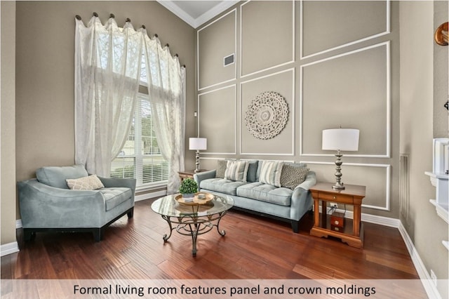 living room featuring visible vents, crown molding, baseboards, wood finished floors, and a decorative wall