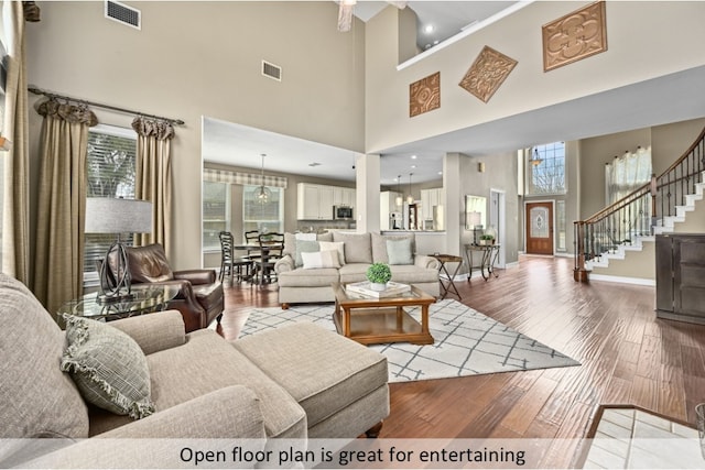 living room featuring stairs, hardwood / wood-style flooring, baseboards, and visible vents