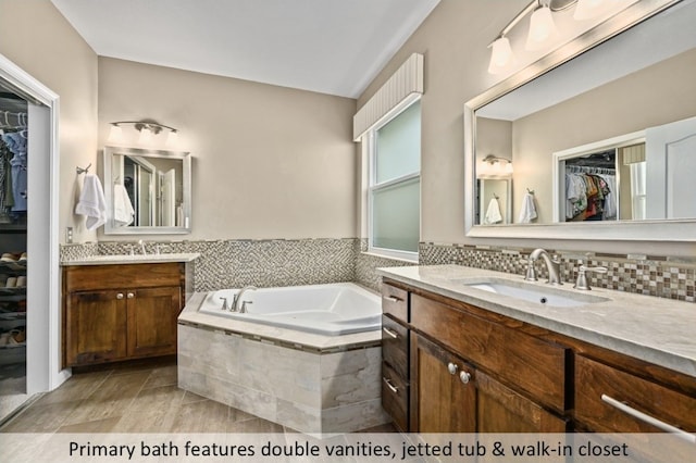 full bathroom with a sink, a garden tub, two vanities, and a spacious closet