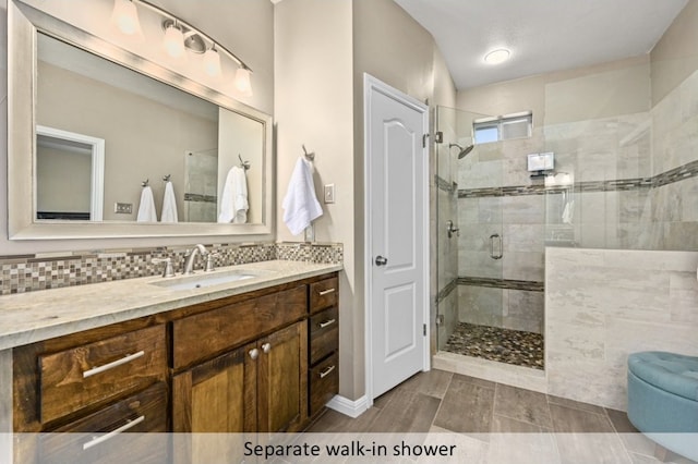 bathroom with vanity, tasteful backsplash, and a stall shower