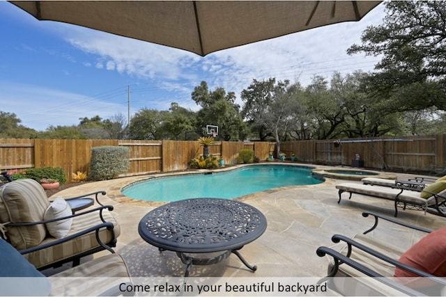 view of swimming pool featuring a patio, a fenced backyard, and a pool with connected hot tub