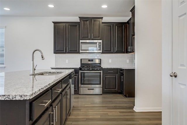 kitchen featuring a sink, stainless steel appliances, backsplash, and dark wood finished floors