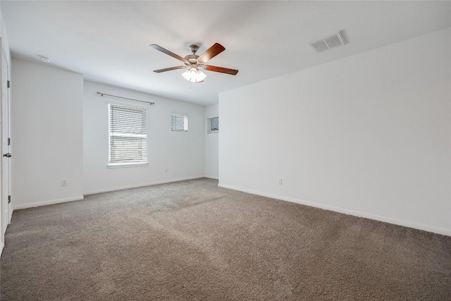 carpeted spare room with visible vents, baseboards, and a ceiling fan