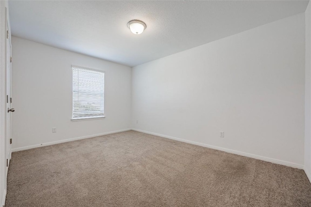 carpeted spare room featuring baseboards