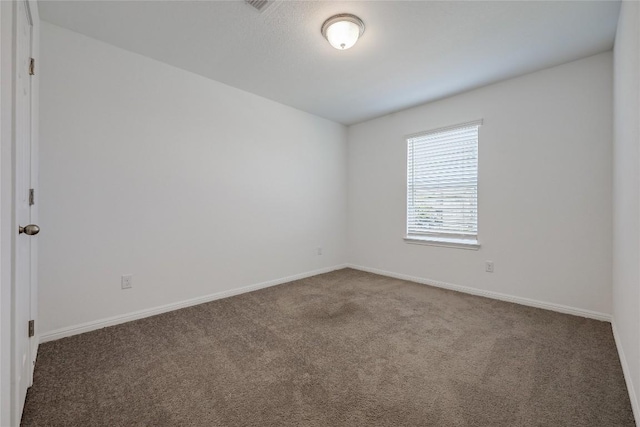 spare room with baseboards and carpet floors