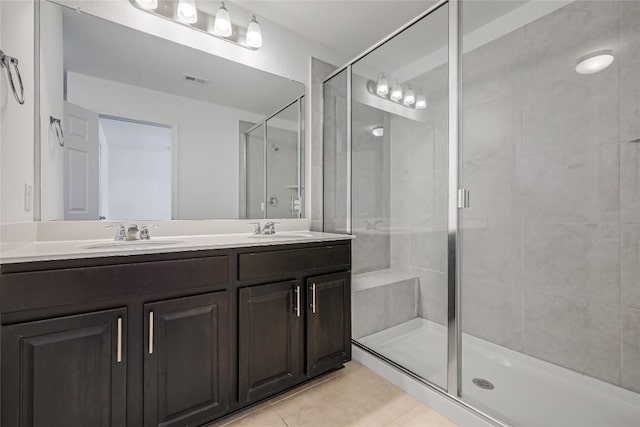 bathroom with tile patterned flooring, a shower stall, double vanity, and a sink