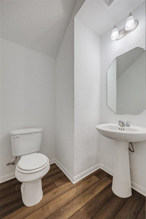 bathroom featuring a sink, toilet, baseboards, and wood finished floors