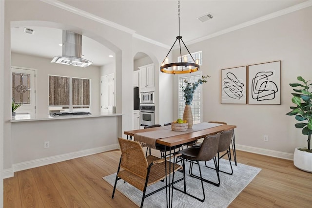 dining space featuring light wood-type flooring, visible vents, baseboards, and ornamental molding