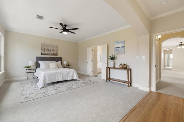 carpeted bedroom with visible vents, arched walkways, baseboards, and crown molding