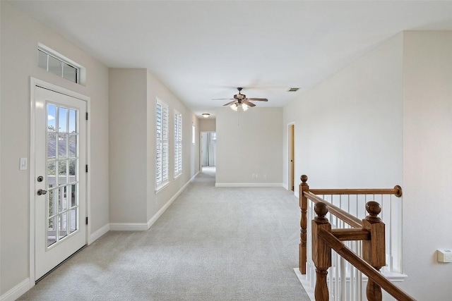 hallway featuring light carpet, visible vents, an upstairs landing, and baseboards