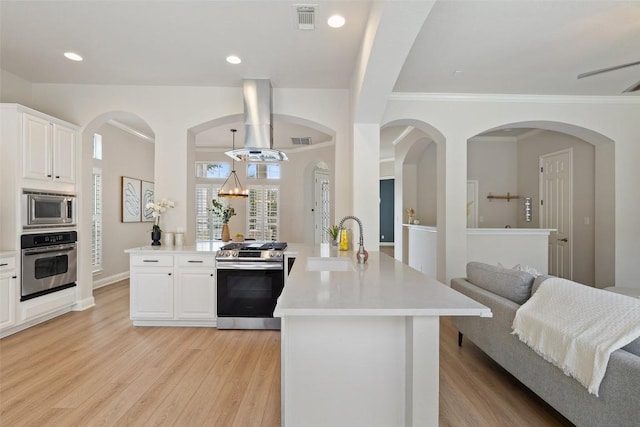 kitchen featuring visible vents, appliances with stainless steel finishes, island exhaust hood, a peninsula, and a sink