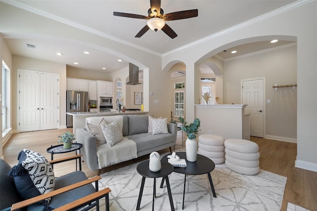 living room featuring visible vents, baseboards, light wood-style flooring, recessed lighting, and arched walkways