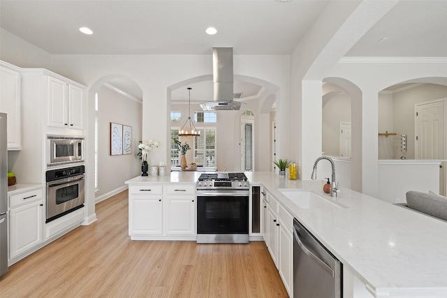 kitchen featuring a sink, island exhaust hood, appliances with stainless steel finishes, a peninsula, and light wood finished floors