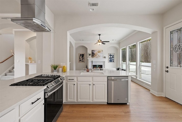 kitchen with visible vents, a sink, stainless steel dishwasher, gas range oven, and wall chimney range hood