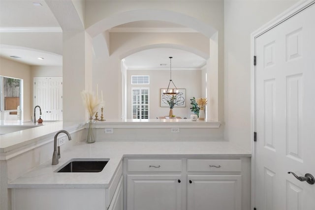 kitchen featuring white cabinets, ornamental molding, and a sink