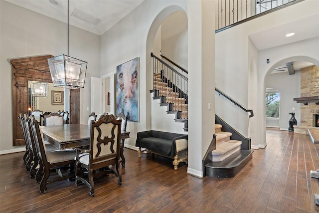 dining space with dark wood-style floors, visible vents, and a towering ceiling