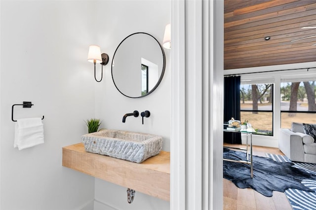 bathroom with a sink, wood ceiling, and baseboards
