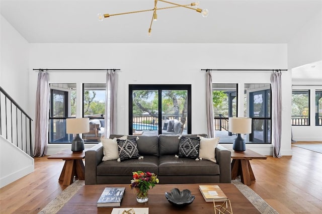 living room with light wood finished floors, stairs, a chandelier, and baseboards