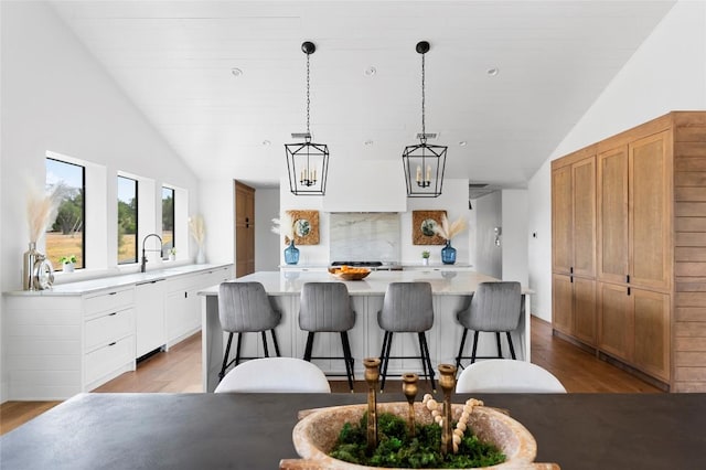 kitchen with dishwasher, vaulted ceiling, light countertops, light wood-type flooring, and a kitchen island