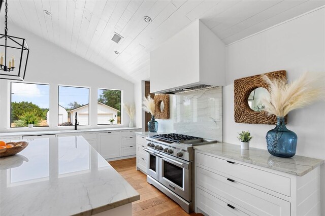 kitchen with visible vents, light wood finished floors, range with two ovens, vaulted ceiling, and backsplash