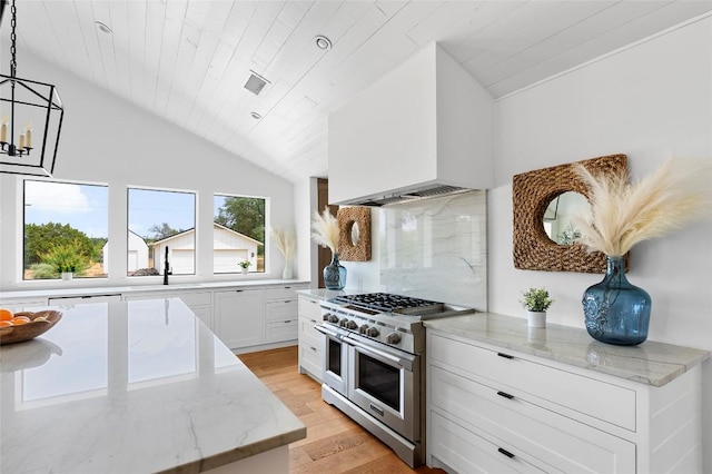 kitchen featuring double oven range, lofted ceiling, light wood-type flooring, light stone countertops, and white cabinets