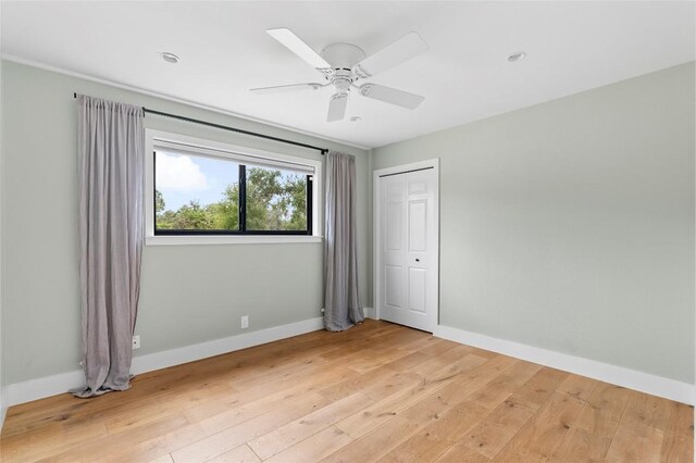 unfurnished bedroom featuring light wood finished floors, a ceiling fan, and baseboards