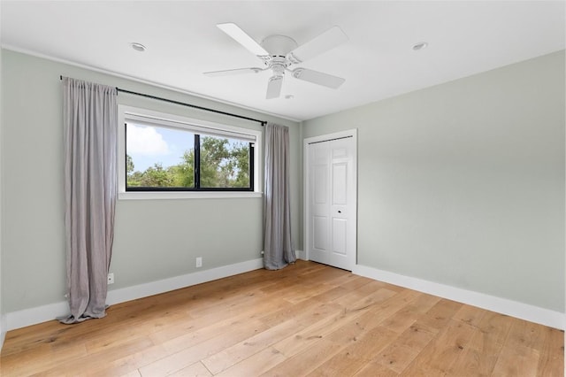 unfurnished bedroom featuring light wood-style flooring, baseboards, ceiling fan, and a closet